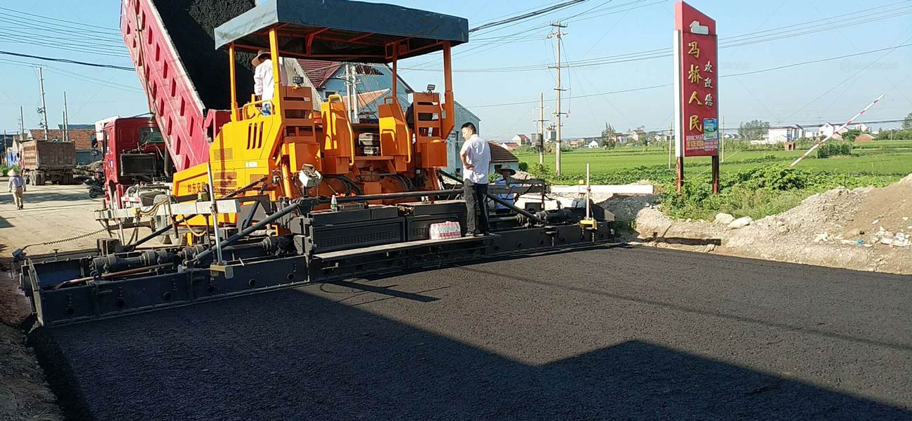 La Máquina Pavimentadora de Asfalto en la Obra de Construcción de Vías