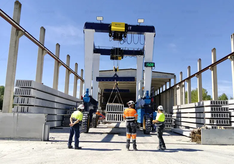 Grúa pórtico móvil de doble viga elevando vigas de hormigón en una planta de prefabricados